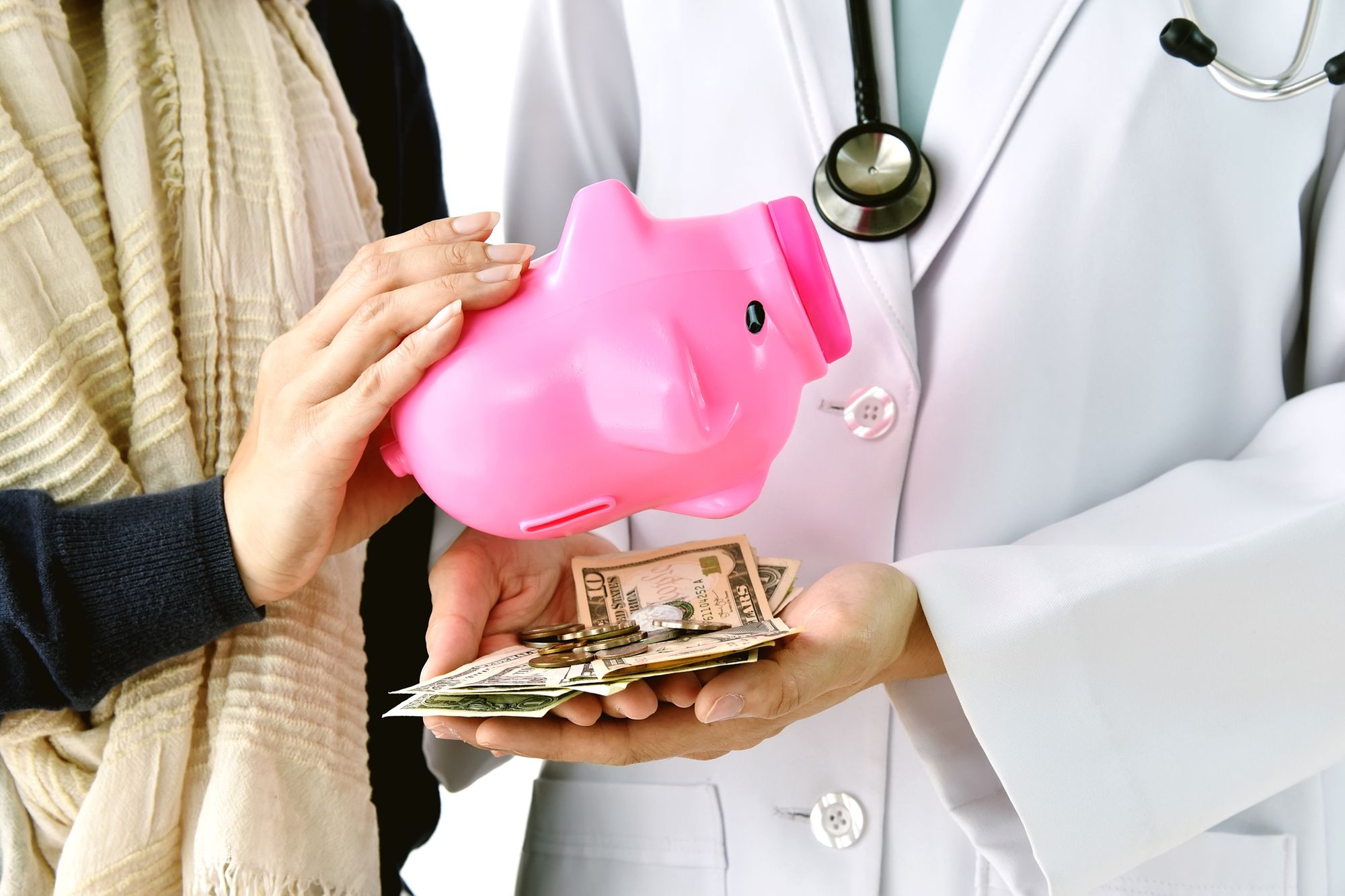 two people holding a piggy bank and some money